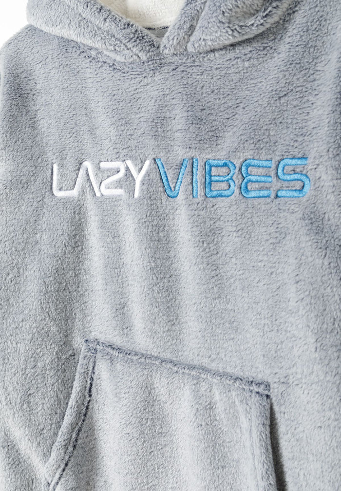 Detail of a grey oversized fleece hoodie with a kangaroo pocket and embroidered 'LAZY VIBES' text.