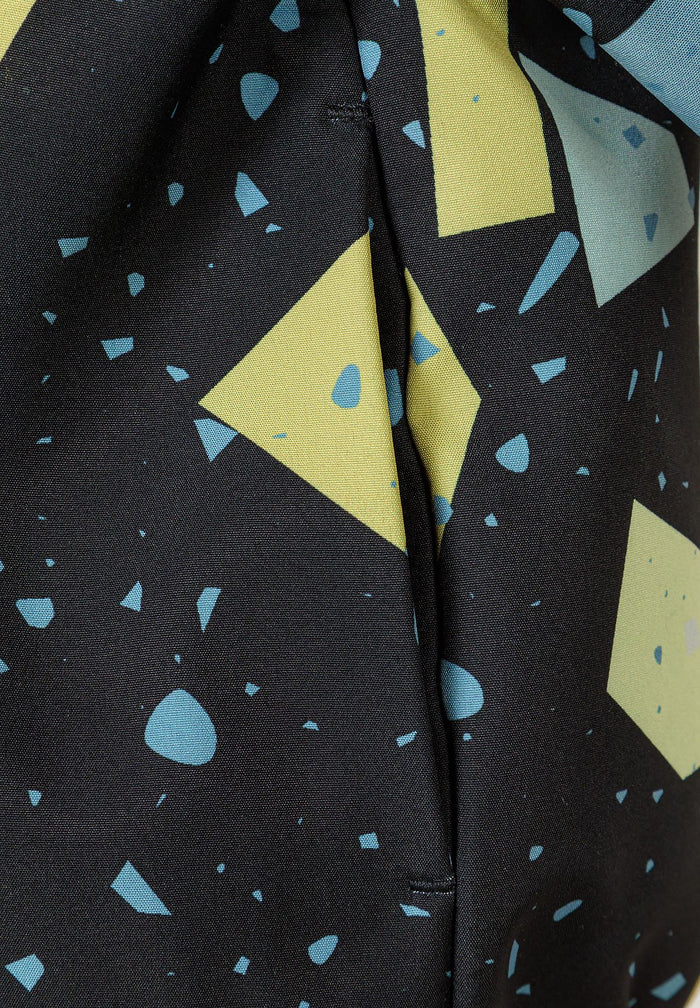 Detail of boys' softshell jacket with abstract print in gunmetal and yellow shapes.