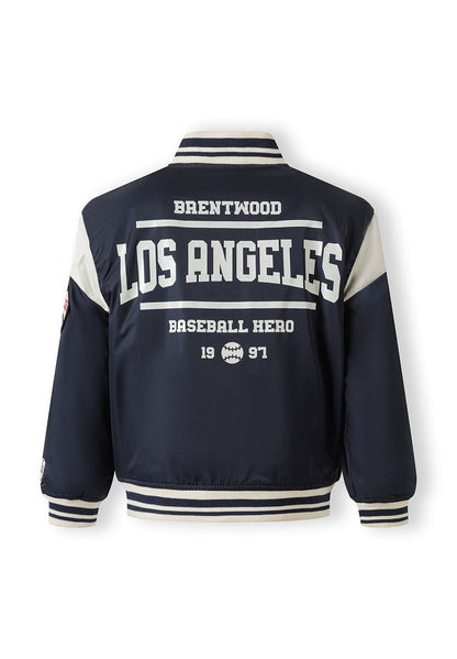 Boys navy varsity bomber jacket, back view with logo and striped cuffs.