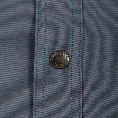 Close-up of a slate blue woven fabric with a single round metal button featuring the 'MURDER WARE' brand name.