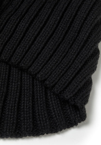 Close-up of a black knitted beanie with ribbed texture and a faux fur pom pom.