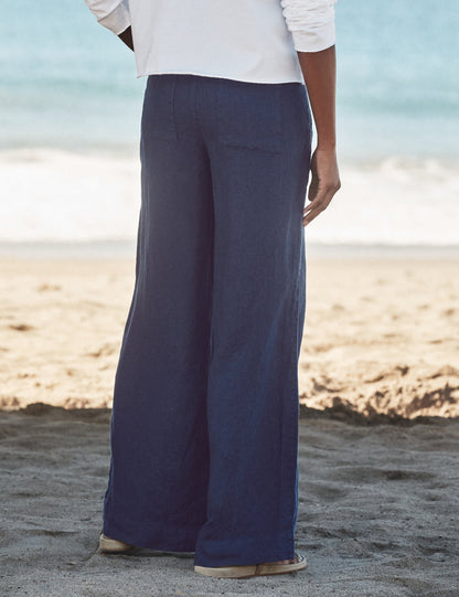 Person wearing navy pants and a white shirt on a beach