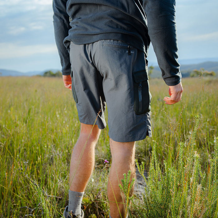 Person walking through a grassy field wearing outdoor clothing