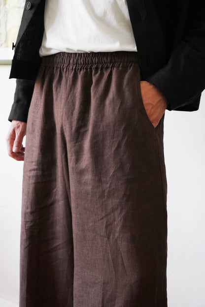 Person wearing brown wide-leg pants with a plain background