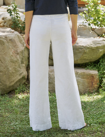 Person wearing white pants standing outdoors with rocks and greenery in the background